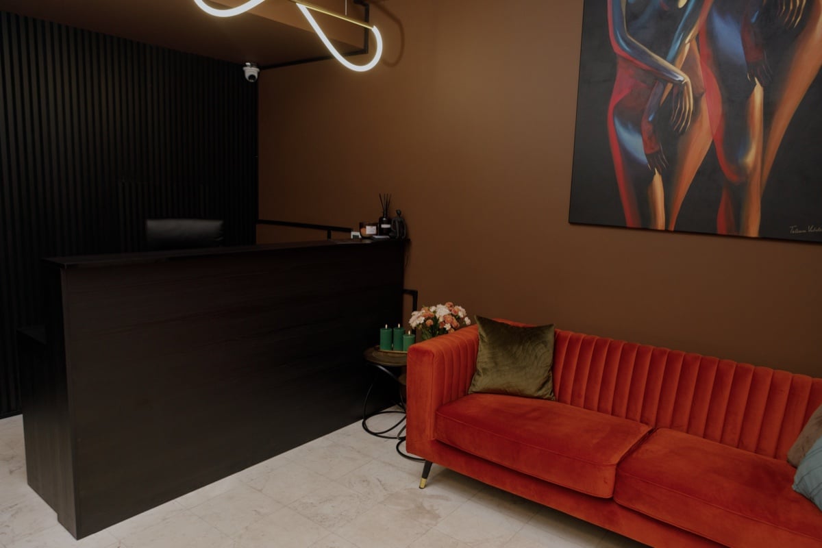 UTOPIA reception: a dark desk, an orange velvet sofa and a neon light overhead